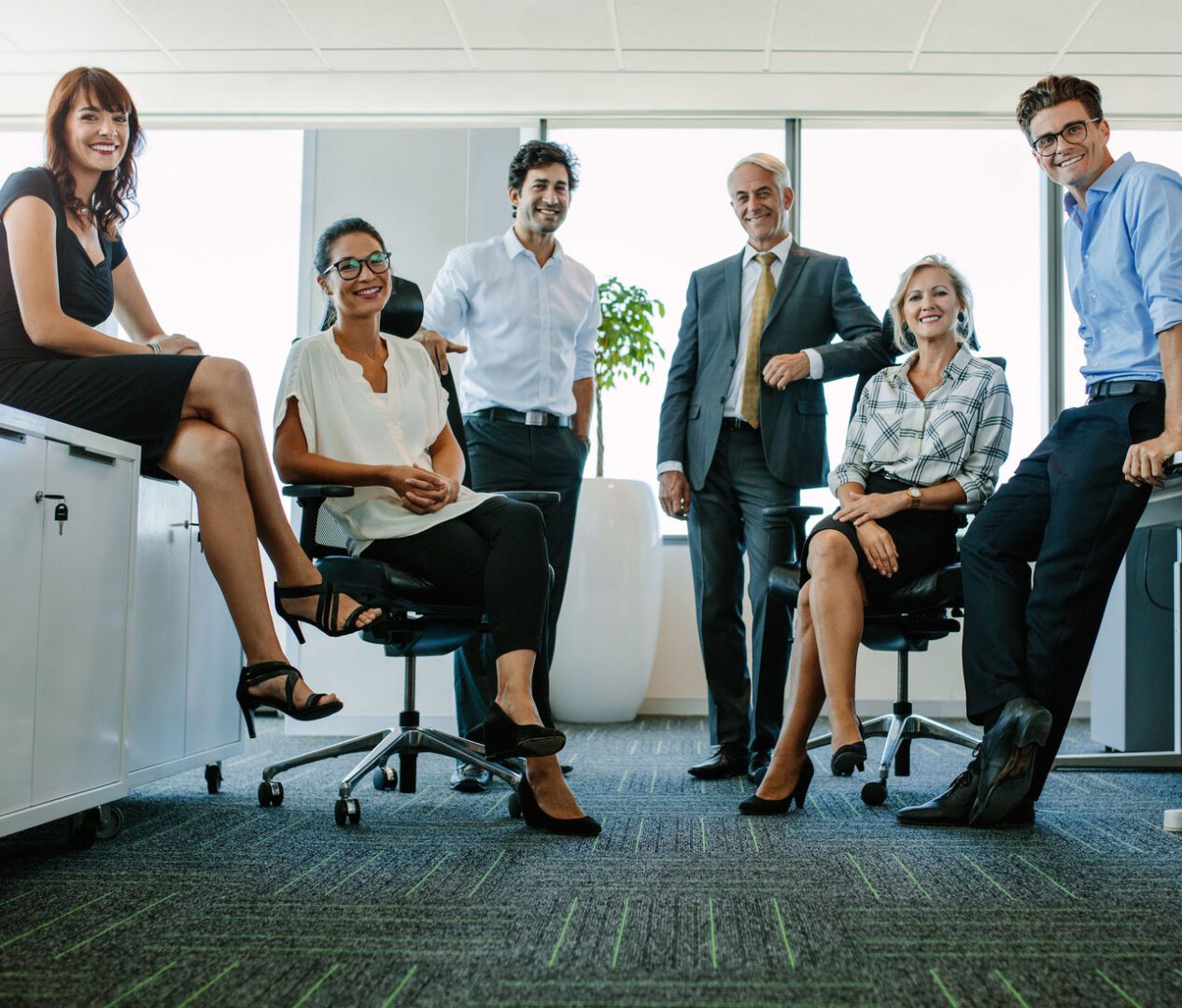 Full length portrait of successful business people looking at camera and smiling. Businessman and businesswoman together in office.
