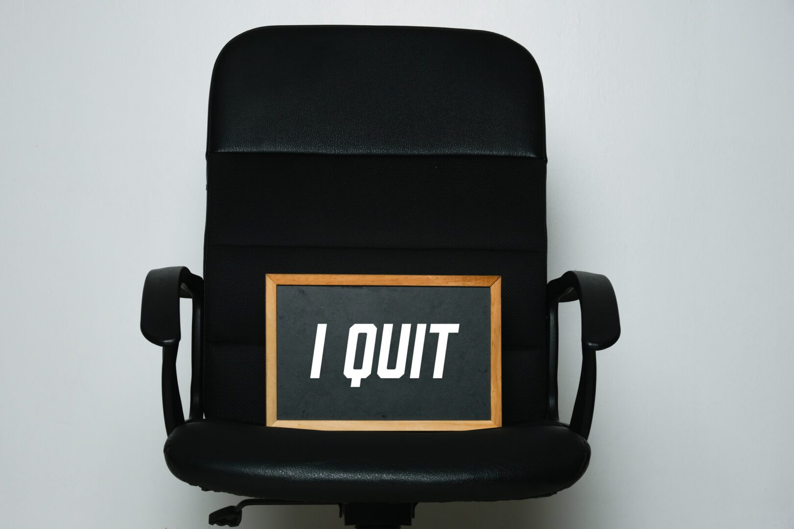 A picture of blackboard with the word written I Quit on the chair. Resignation and quit job concept.